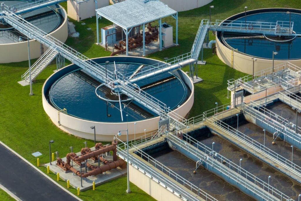 Wastewater treatment plant with circular tanks, walkways, and processing basins.