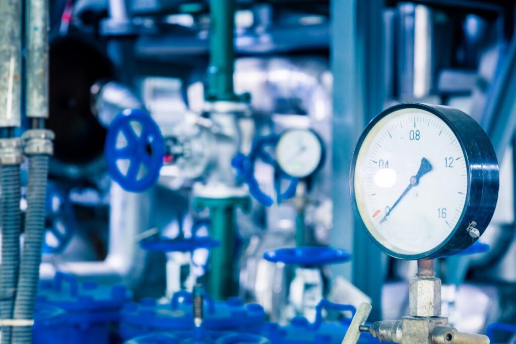 Pressure gauge mounted on industrial piping inside a mechanical plant.