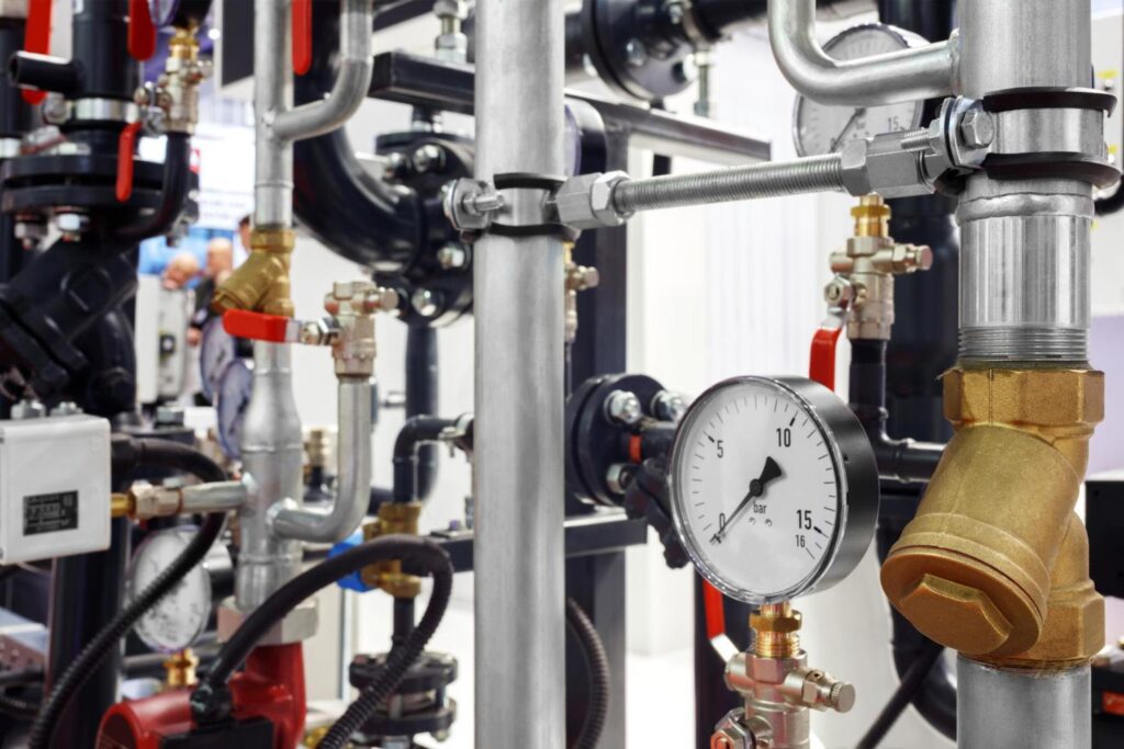 Close-up of an industrial pipe manifold with brass valves and a pressure gauge reading 10 bar.