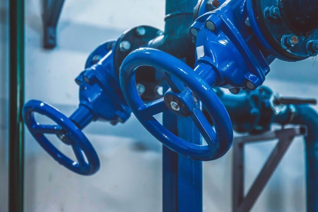 Blue handwheel gate valves installed on a blue-painted industrial pipeline.