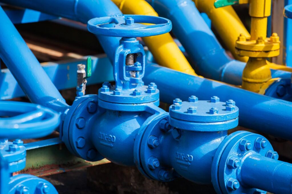 Flanged gate valves with handwheels and rising stems on a pipe rack at an industrial facility.